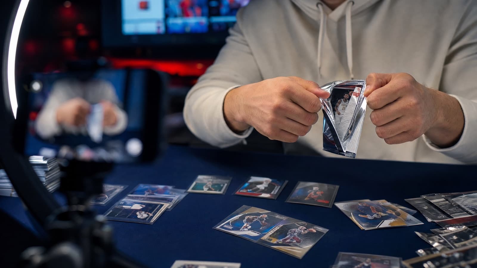 Hands ripping a foil pack of trading cards live on camera during a card break stream